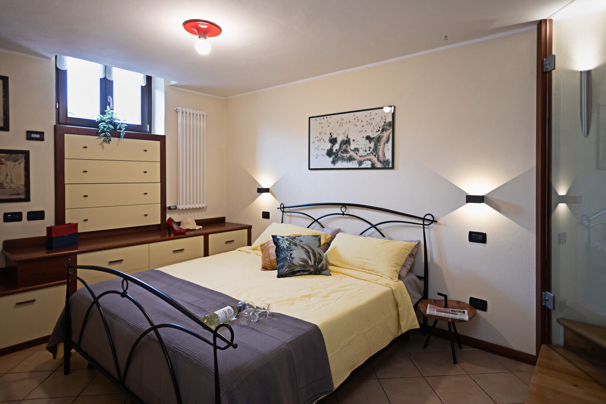 Een slaapkamer met een bed, nachtkastje, lamp en een kaptafel.