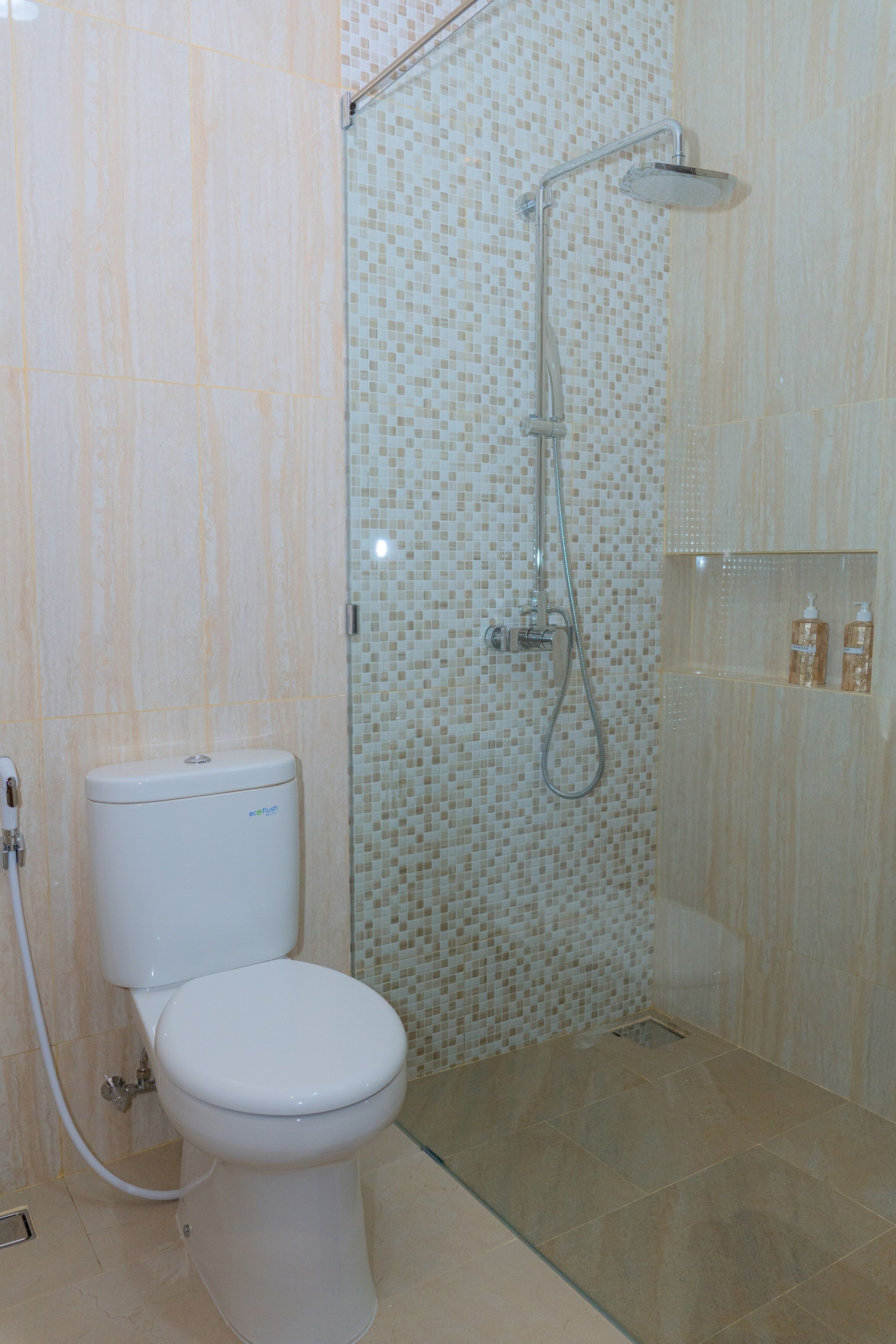 A bathroom with a toilet, a shower with a glass door, and a tiled wall.
