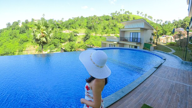 Ein Pool mit Blick auf eine Hügelkulisse und ein Gebäude im Hintergrund.