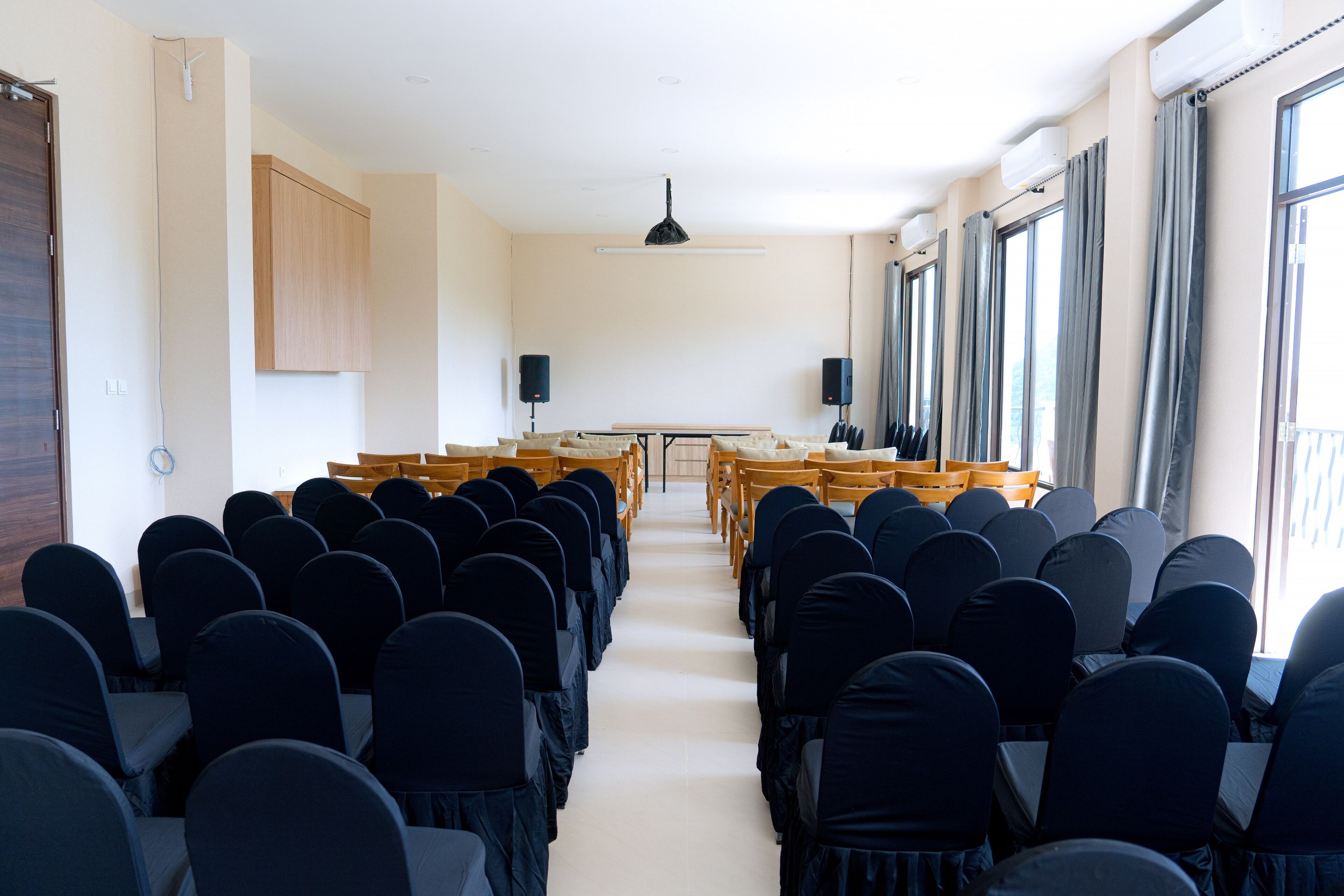 A conference room with rows of chairs, a podium, and speakers.