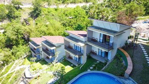 Ein modernes Mehrfamilienhaus mit Balkonen, einem Schwimmbad und üppigem Grün rund um das Anwesen.