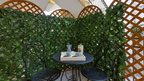 A small outdoor seating area with a table and two chairs, surrounded by a lush green hedge. - 3223 La Casa di Roberta by Barbarhouse (Otranto)