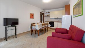 A compact living space with a dining area, kitchenette, and a red sofa. - 3223 La Casa di Roberta by Barbarhouse (Otranto)