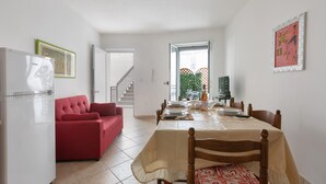 A dining area with a table set for four, a red sofa, and a refrigerator. - 3223 La Casa di Roberta by Barbarhouse (Otranto)