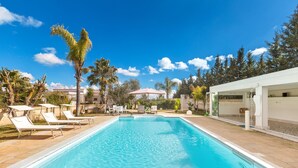 A swimming pool with lounge chairs, a covered seating area, and palm trees. - 3220 Villa Smeralda by Barbarhouse (Guagnano)