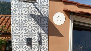 Un baño con pared de azulejos con diseño, un cabezal de ducha y una ventana con vistas al exterior.