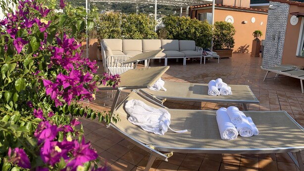 Una terraza en la azotea con sillones de descanso, una zona de estar cubierta y vistas del paisaje circundante.