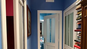 Un pasillo con paredes azules, suelo de baldosas y una estantería llena de libros.