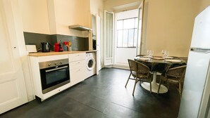 A compact kitchen with a stove, oven, and washing machine, a dining table with chairs, and a refrigerator. - #FF | Pretty light in Grenoble ☀ | T2 (Grenoble)
