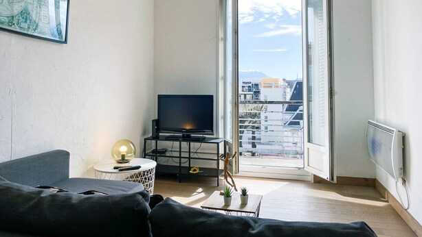 A modern living room with a sofa, a TV on a black stand, a globe lamp, and a small table with plants. - #FF | Pretty light in Grenoble ☀ | T2 (Grenoble)