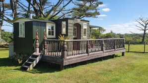 Una casita con una terraza de madera y un cobertizo pequeño.