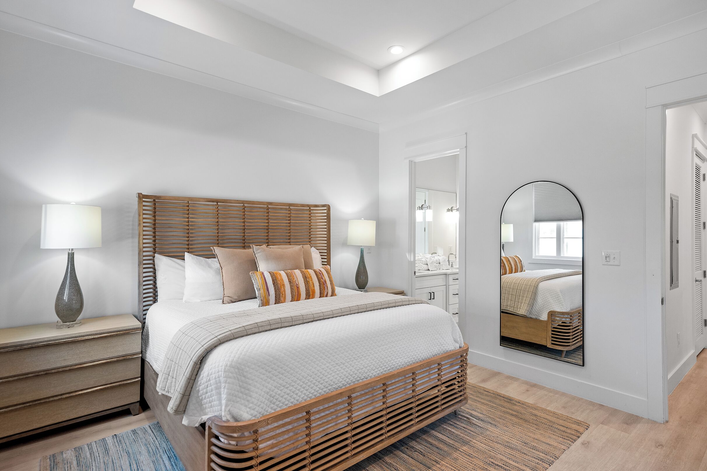 A bedroom with a bed, bedside tables, a mirror, and a door.