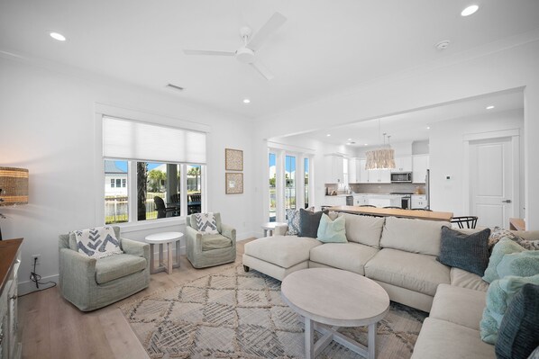 A spacious living area with a large sectional sofa, a round coffee table, and a dining table.