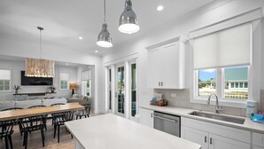 Cocina moderna con gabinetes blancos, una isla grande e iluminación colgante.