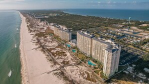 Un complejo turístico costero con edificios altos, una playa y un campo de golf.