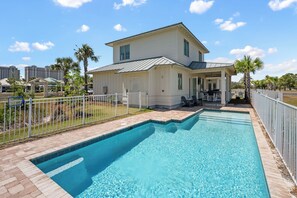 A two-story house with a swimming pool, a covered patio, and a fenced yard.
