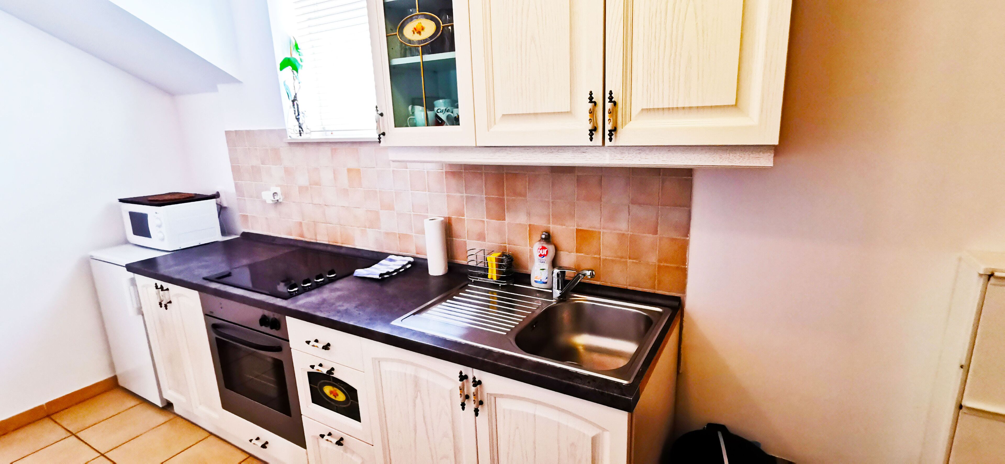 Uma cozinha compacta com micro-ondas, fogão, pia e armários.