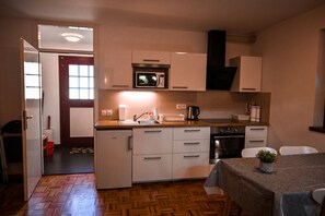 Una cocina compacta con gabinetes blancos, un microondas, un fregadero y una estufa.