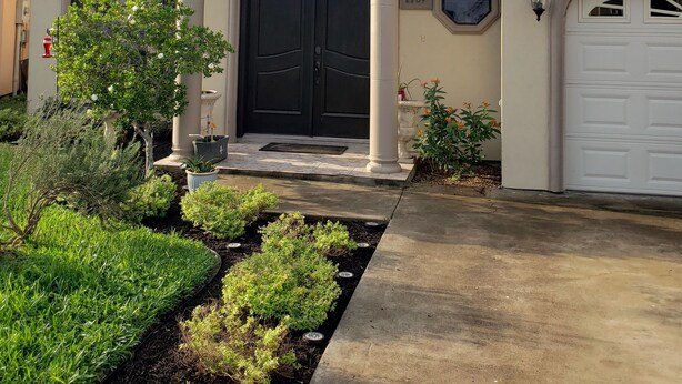 Una casa de dos plantas con una puerta principal negra grande, un garaje y un jardín bien cuidado.