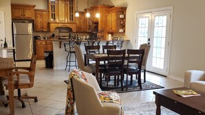 Un salón espacioso con una gran mesa de comedor, asientos cómodos y una zona de cocina con armarios de madera y electrodomésticos modernos.