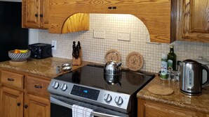 Una cocina con armarios de madera, estufa de acero inoxidable y salpicadero de azulejos.