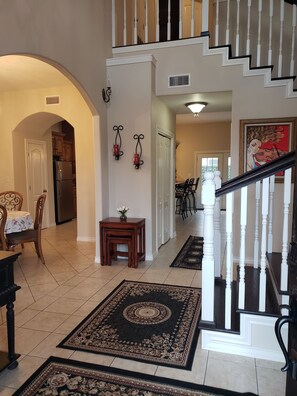 A spacious living area with a kitchen, dining area, and a staircase leading to an upper floor.