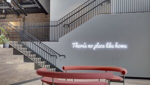 Un interior moderno con un banco rojo, una escalera y una pared con el texto 'There's no place like home'.