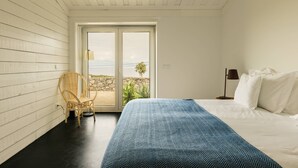 Una camera da letto con un letto, una sedia, una lampada e vista attraverso una porta.