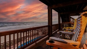 Una terraza de madera con vista al océano y al atardecer.