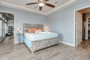 A bedroom with a wooden bed, a ceiling fan, and a bookshelf. - 2 Beachfront Homes, Each with Pool. Sleep 26 (Gilchrist)