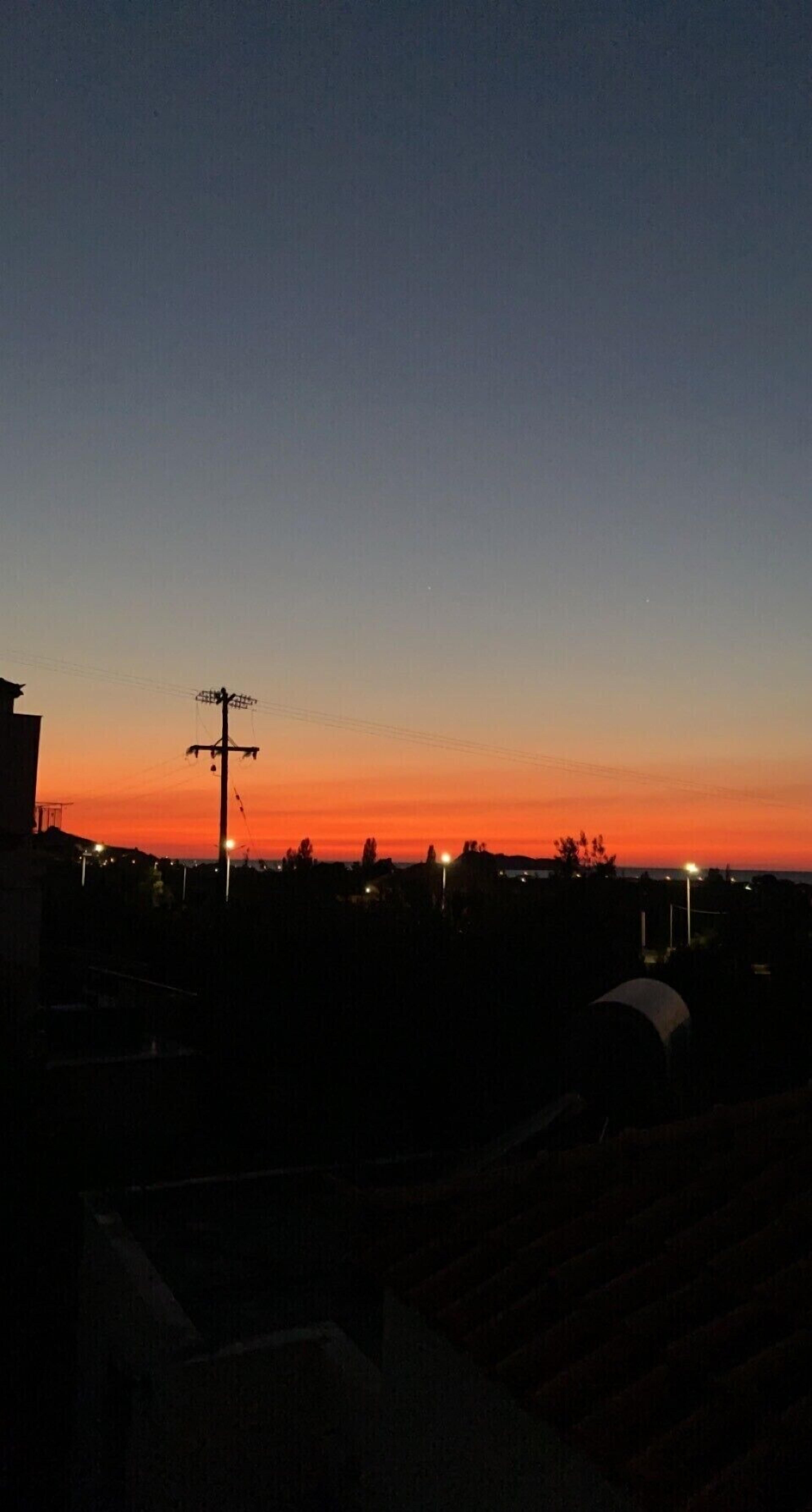 A sunset over a residential area with houses and streetlights.