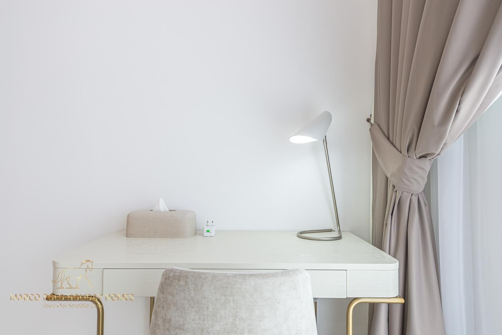 A minimalist desk with a lamp, a tissue box, and a small device on it.