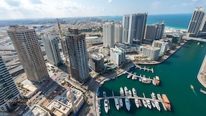 Un port de plaisance où sont amarrés de nombreux bateaux, entouré de grands immeubles et offrant une vue dégagée sur la mer.