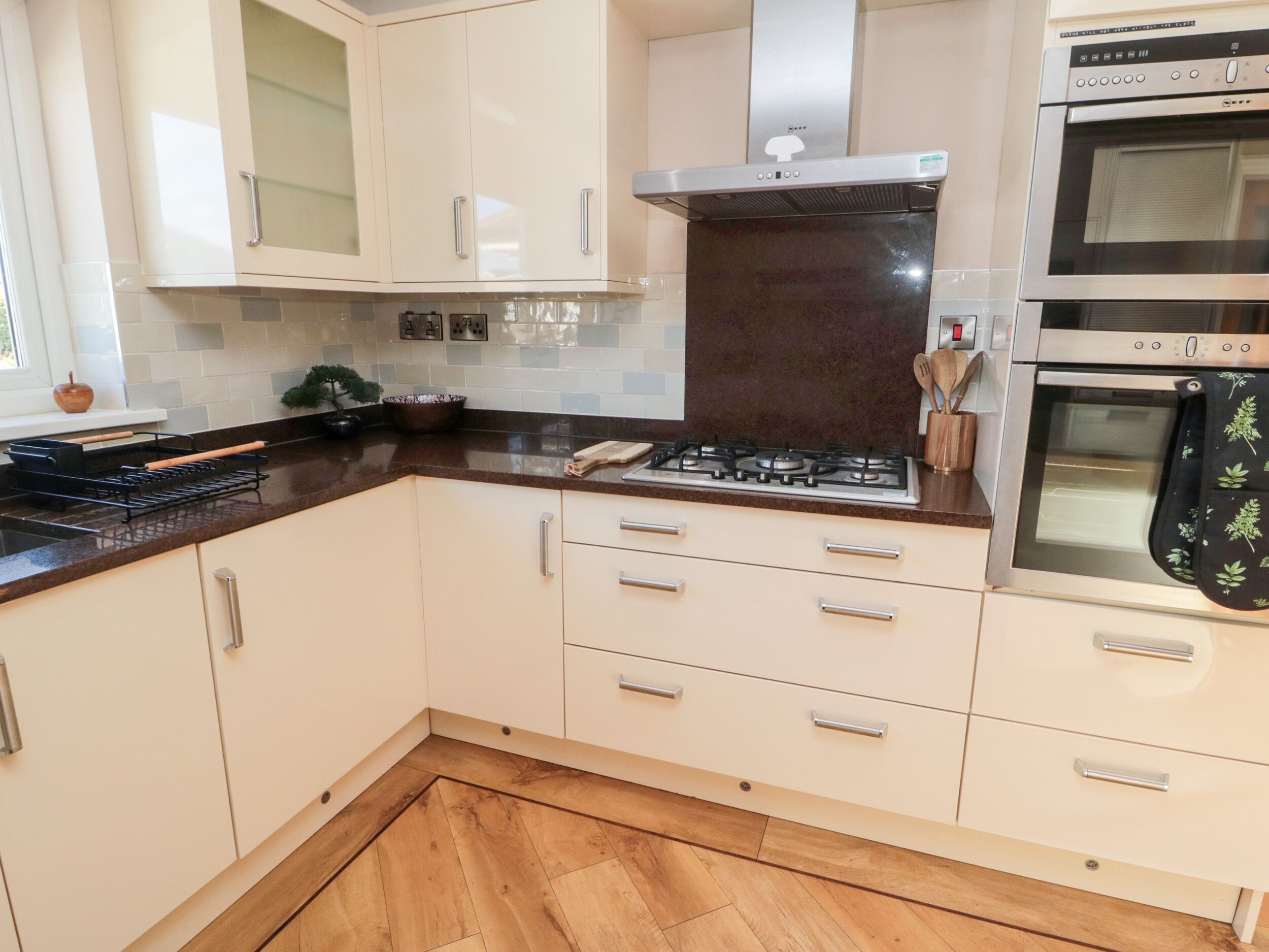 A modern kitchen with white cabinets, a stainless steel stove, and two ovens.
