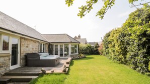 A stone house with a hot tub, a covered patio, and a well-maintained lawn. - The Croft (Alnwick)