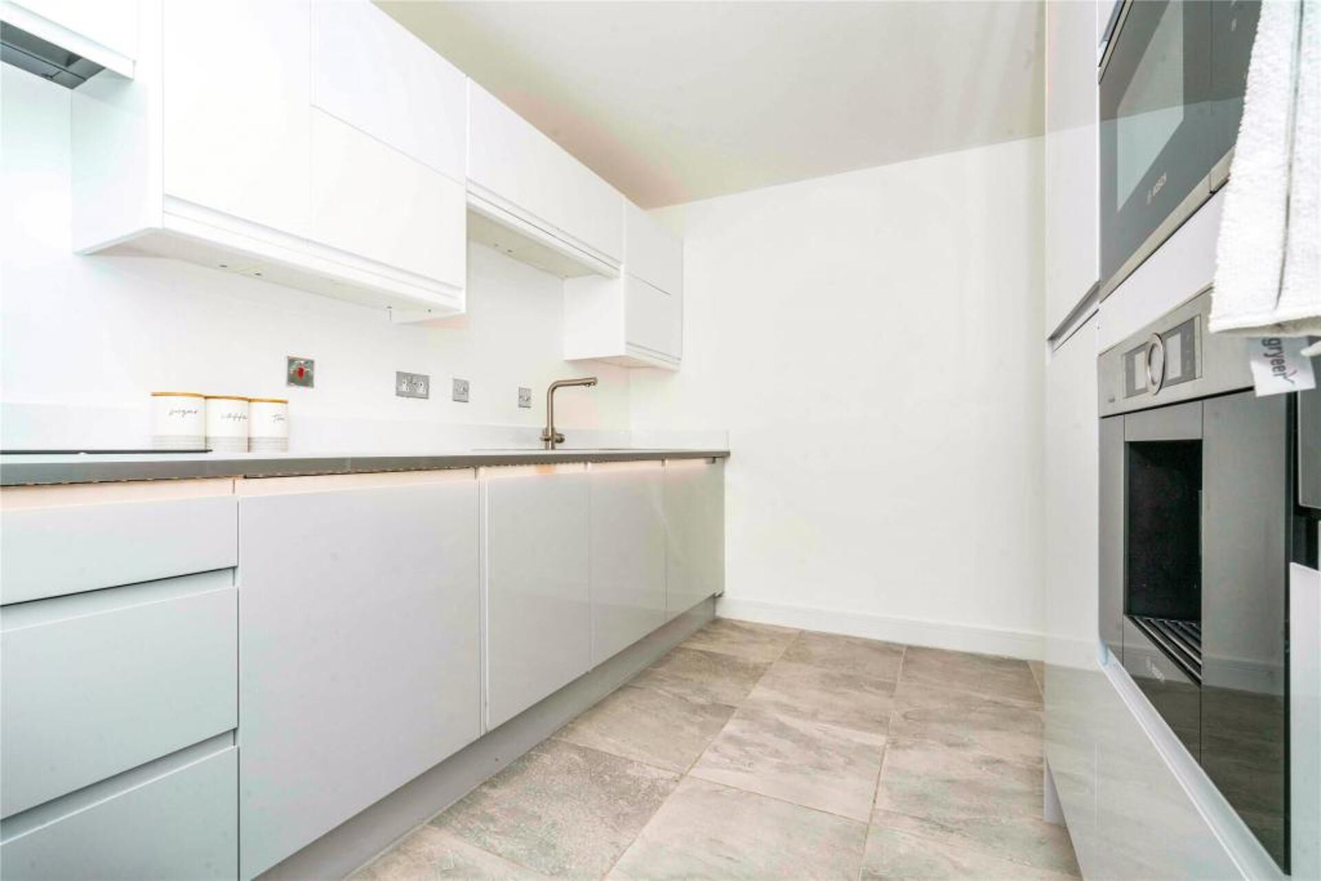 A modern kitchen with white cabinetry, a stainless steel oven, and a tiled backsplash.