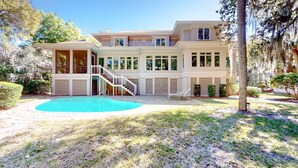 Una casa de dos pisos con piscina, un porche cubierto y una escalera que lleva al piso superior.