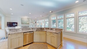 Una cocina moderna con encimera de granito, muebles beige y lavavajillas integrado.