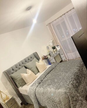 Relax in a serene bedroom with a large bed, tufted headboard, and a cozy bedspread.