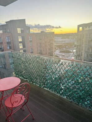 Enjoy the city view from this balcony with a glass partition and seating area.