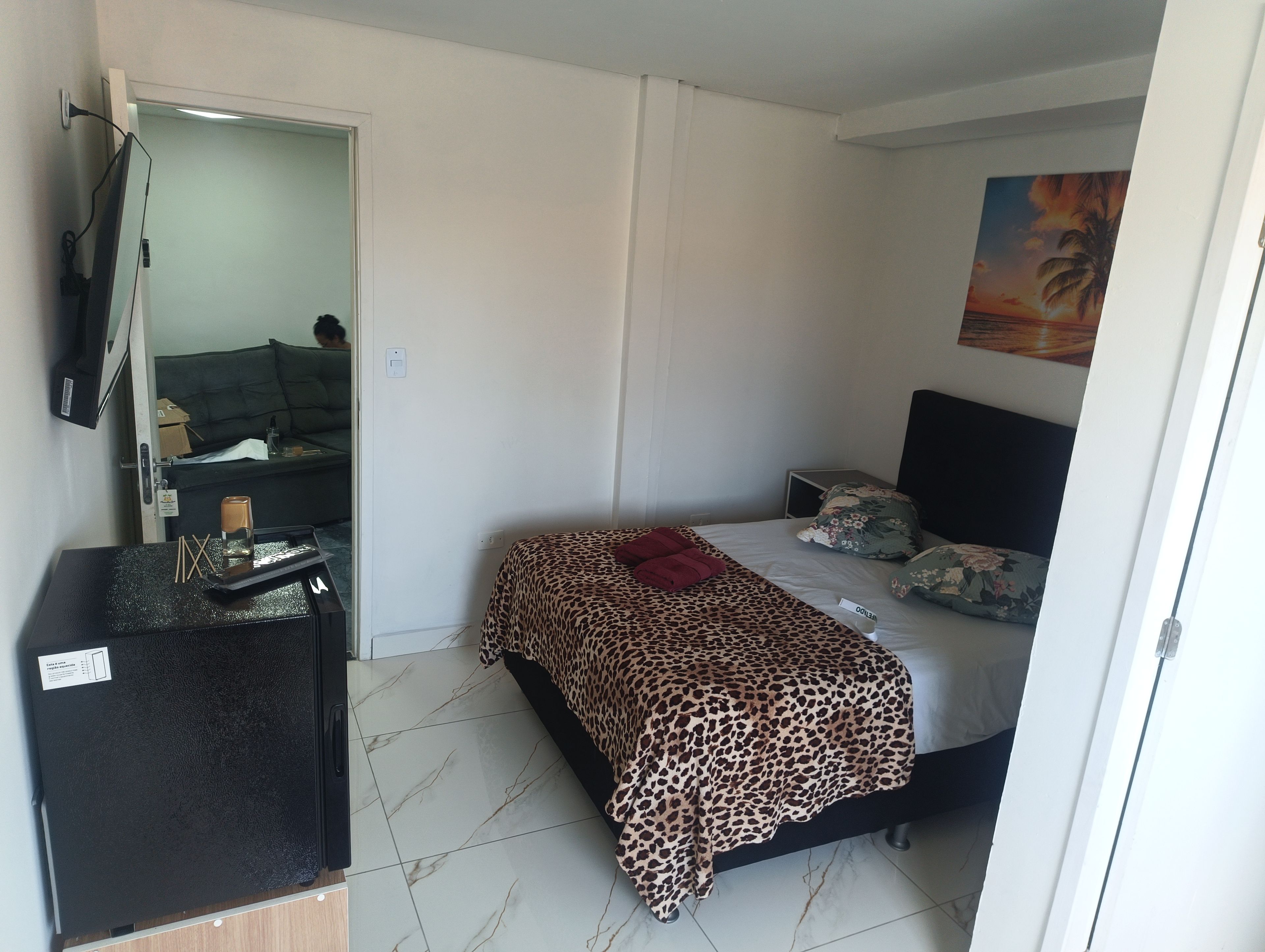 Un dormitorio con cama, escritorio, espejo y un cuadro en la pared.