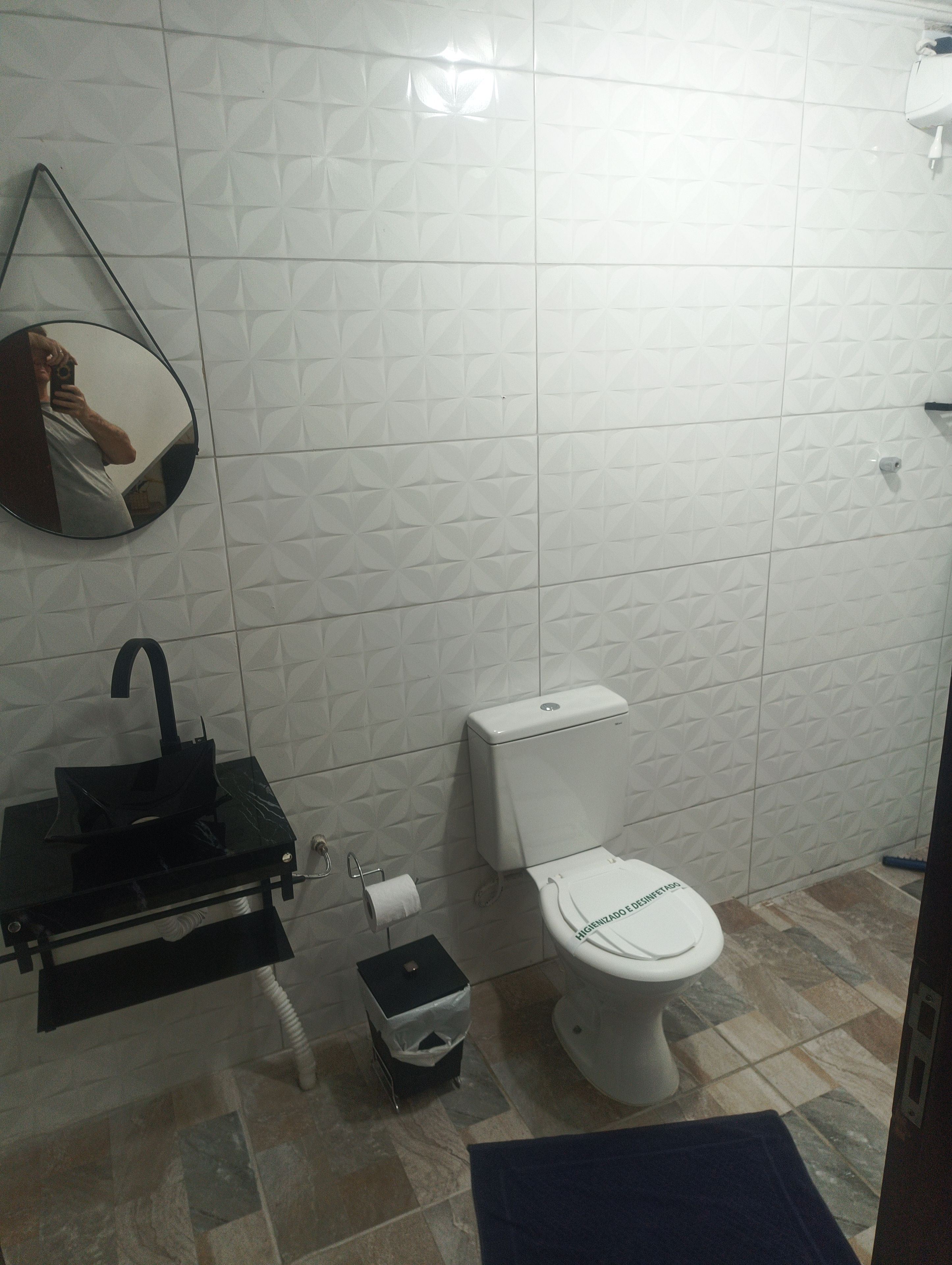 A bathroom with a toilet, sink, and mirror.