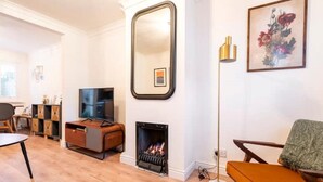 Un salon avec une cheminée, un téléviseur et un grand miroir.