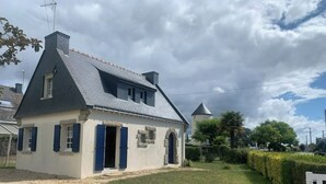 Een klein, laag huis met schuine kap en een stenen fundering.