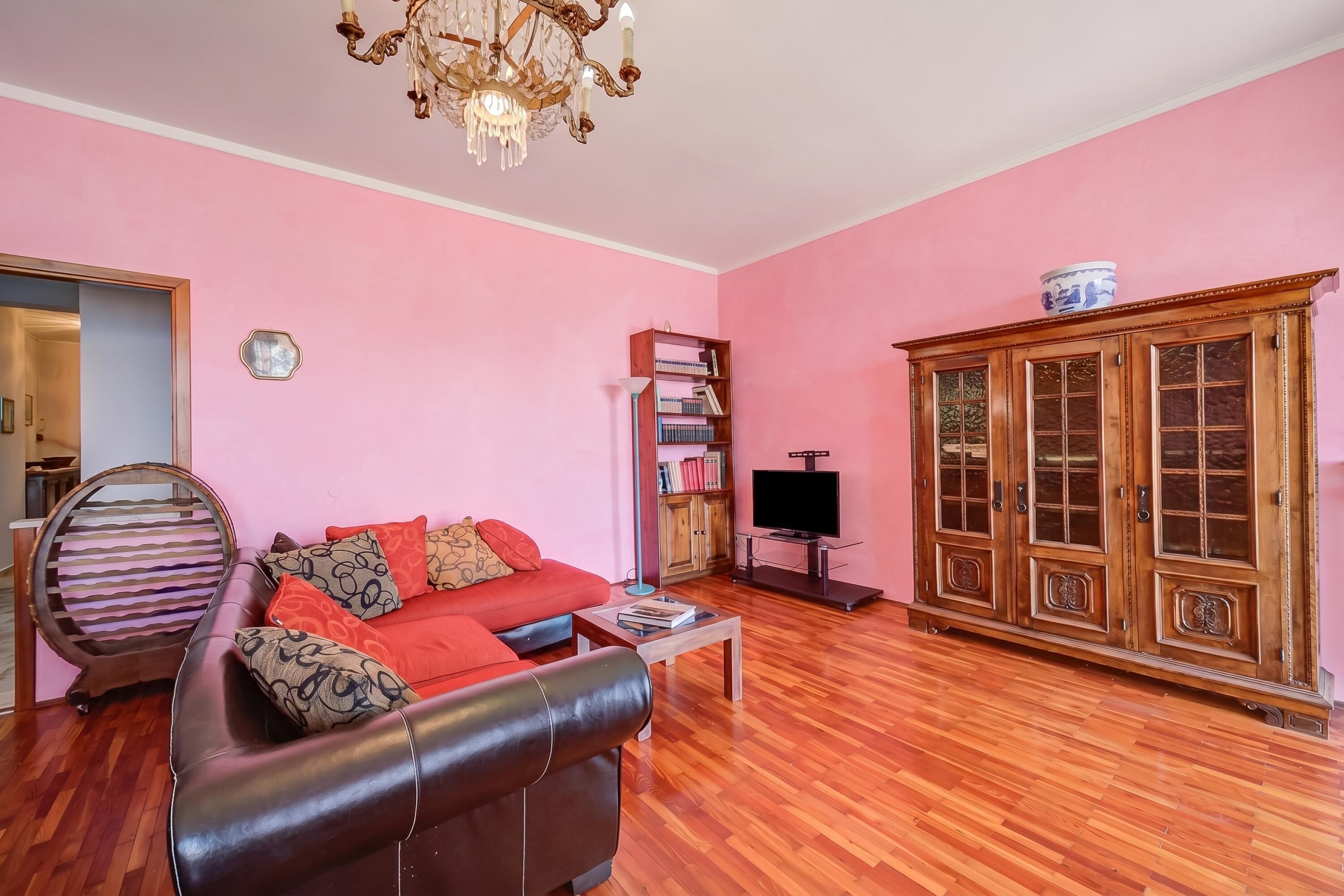 A living room with a leather sofa, a wooden cabinet, and a television.