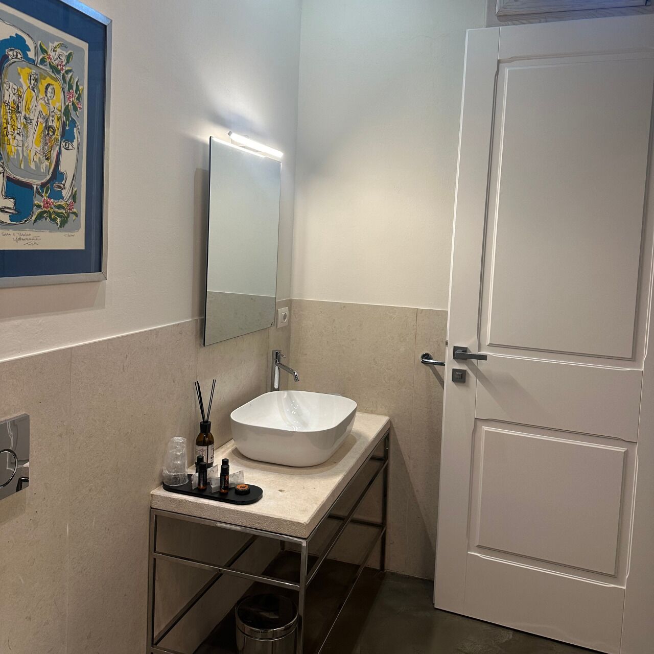 A bathroom with a white sink, a mirror, and a door.
