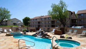 A hotel with a swimming pool, lounge chairs, and a waterfall feature. - WW F101 Slice of Heaven (New Braunfels)