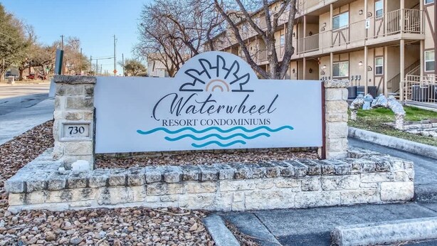 A sign for Waterwheel Resort Condominiums with a stone base and a clear sky in the background. - WW F101 Slice of Heaven (New Braunfels)