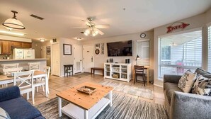 A spacious living area with a dining table, sofas, a coffee table, and a TV. There is a kitchen area with cabinets and a refrigerator. - WW F101 Slice of Heaven (New Braunfels)