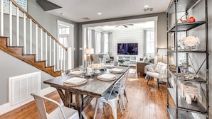 A spacious living room with a wooden dining table, comfortable seating, and a bookshelf. - Carlton Landing-Goose Bay (Carlton Landing)